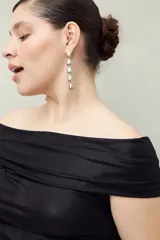 Top negro con escote off-shoulder, confeccionado en tejido de punto con efecto satinado y corte ajustado.