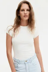 Remera blanca de punto acanalado fino, con cuello redondo y mangas cortas con ribete de encaje.