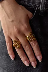 Anillo dorado ajustable de acero quirúrgico hipoalergénico, con diseño de gotas irregulares.