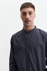 Camisa azul de manga larga con cuello mao y cartera abotonada.