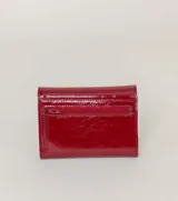 Billetera plegable color azul con textura de cuero croco y cierre a presión metálico con logo de flor de lis.