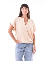 Blusa color beige con estampado de pequeñas hojas marrones, escote en V y mangas cortas.