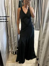 Vestido largo de silueta fluida confeccionado en seda con detalles de encaje. Presenta un diseño negro con estampado de lunares blancos, escote en V profundo y espalda descubierta con tiras cruzadas. La falda cuenta con paneles de encaje que aportan movimiento y delicadeza.