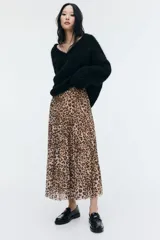 Pollera midi de malla plisada con estampado de leopardo, corte evasé, elástico en la cintura y forro de punto.