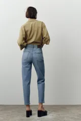 Jeans de tiro alto color celeste, corte mom fit, con cinco bolsillos y cierre frontal con cremallera y botón.