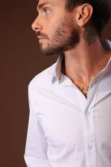 Camisa blanca de manga larga con cuello clásico y cierre frontal con botones.