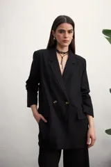 Blazer negro de corte recto con solapas de muesca, cierre cruzado con dos botones dorados, bolsillos delanteros con solapa y mangas largas.