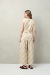 Mono enterito de algodón con rayas verticales color verde claro y beige, con cuello en V, sin mangas, con cierre frontal con botones y cinturón de lazo.