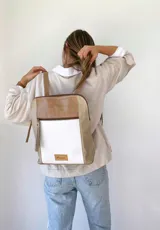 Mochila beige con detalles en blanco y marrón.