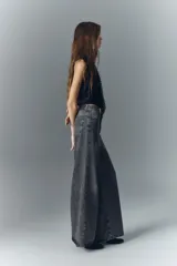 Jean oxford tiro alto de denim negro con lavado stone y bigotes. Pierna ancha desde la cadera.