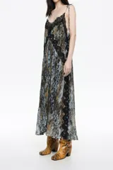 Vestido largo de corte línea A, confeccionado en tejido plisado con estampado de piel de serpiente en tonos marrón, negro y celeste. Presenta escote en pico pronunciado con tirantes de lazo ajustables y detalles de encaje negro en el escote y a lo largo del frente y laterales.