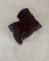 Botín corto de cuero vacuno color beige, estilo cowboy, con caña media y costuras decorativas en forma de onda en el empeine. Presenta un taco bajo y suela con pespunte visible.