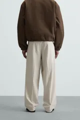 Pantalón de vestir color beige, corte wide fit, con cintura elástica, pliegues frontales, bolsillos laterales y traseros de vivo.