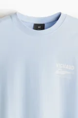 Remera celeste de algodón con cuello redondo y estampado frontal con la palabra "VIGNAUD" y un dibujo de una lancha.