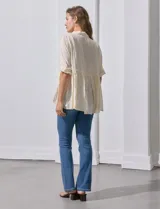 Blusa color crema de crepe con cuello a la base con solapa, escote en V con abertura central y botones. Delantera con detalles plisados y apliques en crochet. Manga corta con terminación fruncida y ruedo en broderie.