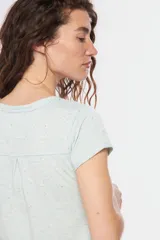 Remera color beige con escote redondo, manga corta, bolsillo en el pecho y cierre parcial con botones.