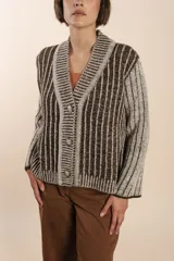 Cárdigan tejido a rayas verticales marrones y beige, con cuello esmoquin, cierre frontal con botones y corte holgado. Tejido en 100% lana fina sin teñir.