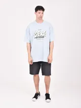 Remera celeste de corte oversized con estampado frontal con la palabra 'Stuck' y una frase en inglés.