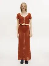 Top tejido calado color azul petróleo con cuello en V y botones carey. Tiene mangas cortas y puños en color amarillo contrastante.