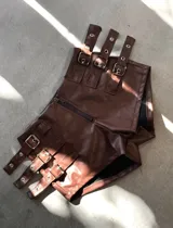 Short negro de cuerina con cierre frontal y múltiples correas con hebillas plateadas.
