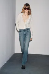 Pantalón de jean azul oscuro, de tiro bajo, corte slim fit y bootcut. Con cinco bolsillos y cierre frontal con cremallera y botón.