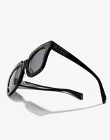 Lentes de sol Hawkers de acetato color negro con apliques de strass plateados en el frente del marco.
