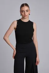Musculosa marrón de tejido liso, con cuello redondo y tachas metálicas decorativas en los hombros.