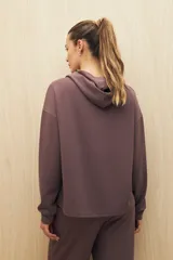 Canguro marrón con capucha, corte amplio y detalle de recorte frontal.