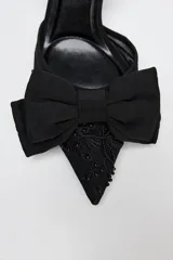 Zapato destalonado negro con tacón fino, capellada de mesh bordado y lazo decorativo en la parte delantera.