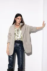 Cardigan de paño color beige, estilo chaqueta, con cuello esmoquin, corte amplio y bolsillos laterales.