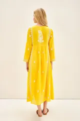 Vestido amarillo largo hasta los tobillos, con cartera de botones símil nacar en el delantero y bordado a contratono a lo largo de toda la prenda.
