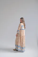 Vestido largo color beige con estampado abstracto en tonos marrones y azules, con cuello mao, mangas largas con puños elásticos y cierre frontal con botones.