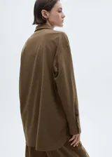 Camisa marrón con rayas verticales finas, de corte oversize, manga larga con puños abotonados, cuello camisero, bolsillo de parche en el pecho y cierre frontal con botones.