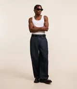Pantalón de jeans azul oscuro, corte amplio tipo skater, con cintura con trabillas, cierre tradicional, bolsillos y costuras contrastantes.
