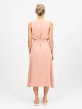 Vestido midi sin mangas de color salmón, con escote en V y abotonadura frontal. Cuenta con un lazo en la cintura para ajustar el calce.