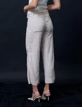 Pantalón capri de lino color beige con estampado floral, marca Zac & Rachel. Tiene pretina con pasadores, cierre y botón. Incluye cinturón de cordones con hebilla metálica. Presenta bolsillos delanteros con botones y bolsillos traseros.