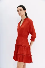 Vestido corto color ladrillo, de mangas largas con puños elásticos, escote en V y falda con volados.