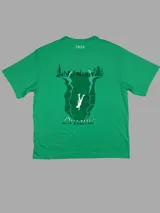 Remera verde con estampado en la espalda de una ciudad y una persona cayendo en un río.
