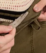 Pantalón flare color verde militar confeccionado en sarga con elastano, tiro alto, cintura ancha con trabillas, doble botón, cierre por cremallera, bolsillos y detalle de recortes.