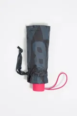 Paraguas plegable con funda cilíndrica de tela estampada con el logo de Bimba y Lola en tonos grises y negros. La base de la funda es de color fucsia y tiene un cordón de sujeción fucsia.