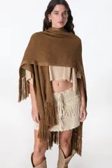 Ruana color beige de tejido de punto con flecos en el ruedo.