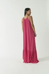 Vestido largo fucsia con breteles finos y escote en V. Presenta un corte a la altura de las rodillas con volados.