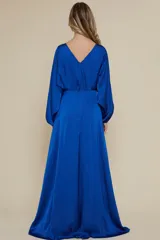 Vestido largo de fiesta color azul eléctrico, confeccionado en satén. Tiene mangas largas abullonadas con puños elásticos, escote redondo y tajo lateral alto.