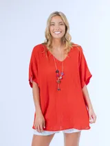 Remerón italiano confeccionado en bambula color naranja, con escote en V y calce oversized. Incluye collar largo con cuentas de colores y dije de estrella.