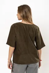 Remera color verde militar de gamuza, con cuello redondo, mangas cortas y detalle de cordones ajustables en el ruedo.