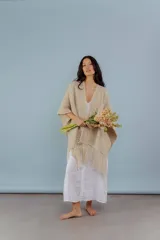 Ruana de lana merino color beige, tejida a mano con detalles de brillos y flecos.