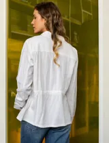 Sobrecamisa blanca de lino y rayón, marca Dash. Tiene cuello solapa, abertura central con botones, bolsillos delanteros y jareta interna de ajuste en la cintura.