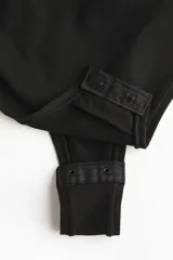 Body negro de microfibra con breteles finos, copas forradas con relleno extraíble, corte alto atrás y refuerzo interior con botones a presión ocultos.