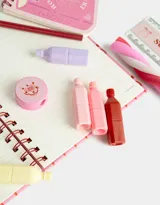 Set de librería en estuche transparente con borde rosado y tiras. Incluye cuaderno A5 de tapa dura con espiral de 80 hojas rayadas, anotador espiralado de hojas lisas, 5 mini resaltadores (amarillo, rosa, celeste, lila y naranja), regla de 15 cm, lápiz de grafito, goma y sacapuntas.