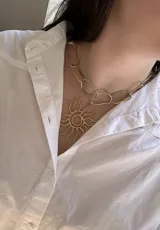 Collar dorado con cadena de eslabones grandes y dije con forma de sol.